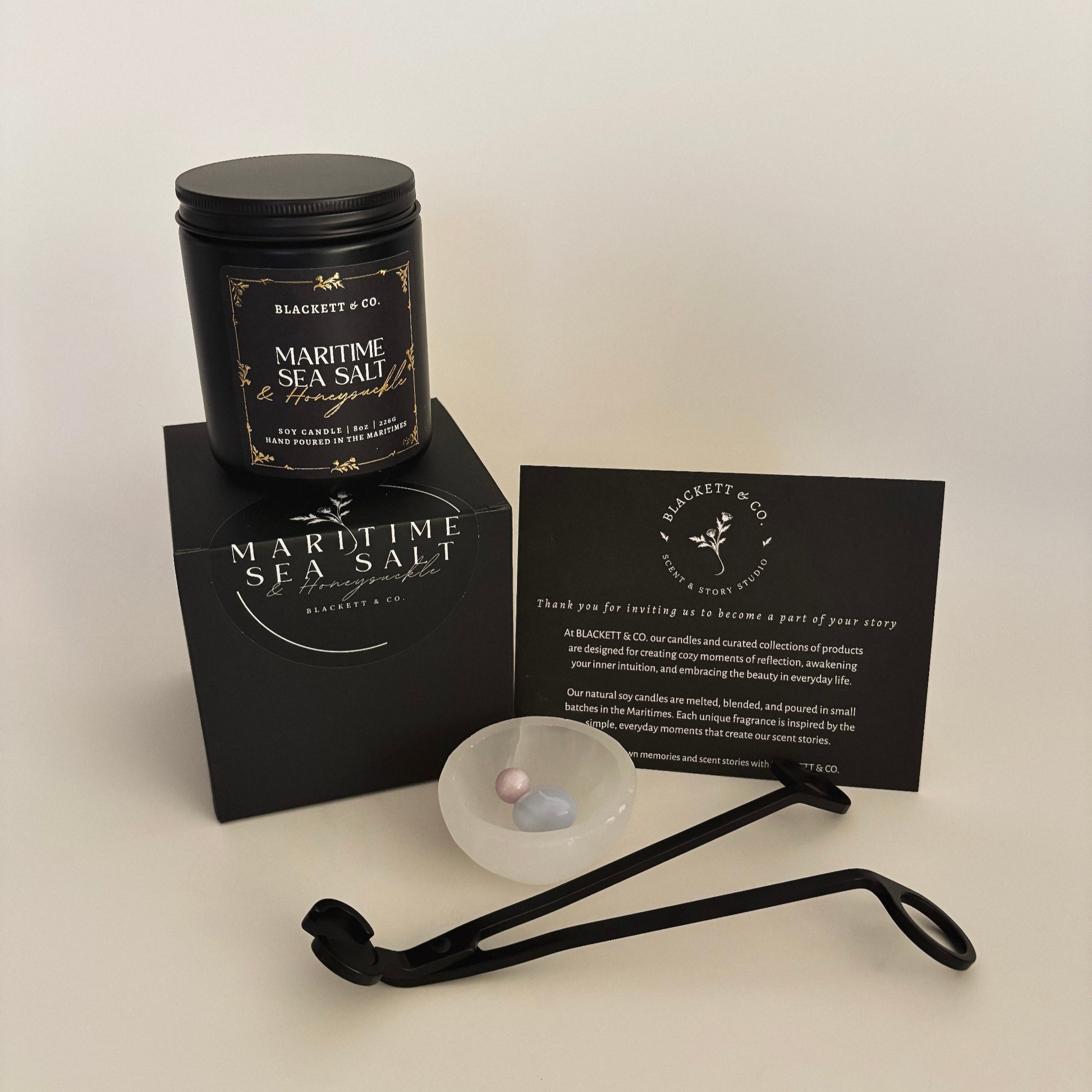 Blackett & Co.'s signature set features a Maritime Sea Salt & Honeysuckle scented natural soy candle, a matte black wick trimmer, a chalcedony heart stone, and kunzite sphere