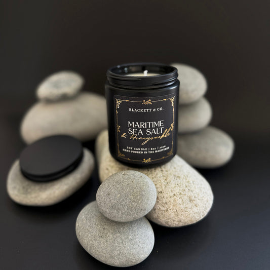 Maritime Sea Salt & Honeysuckle scented natural soy candle on a stack of beach rocks