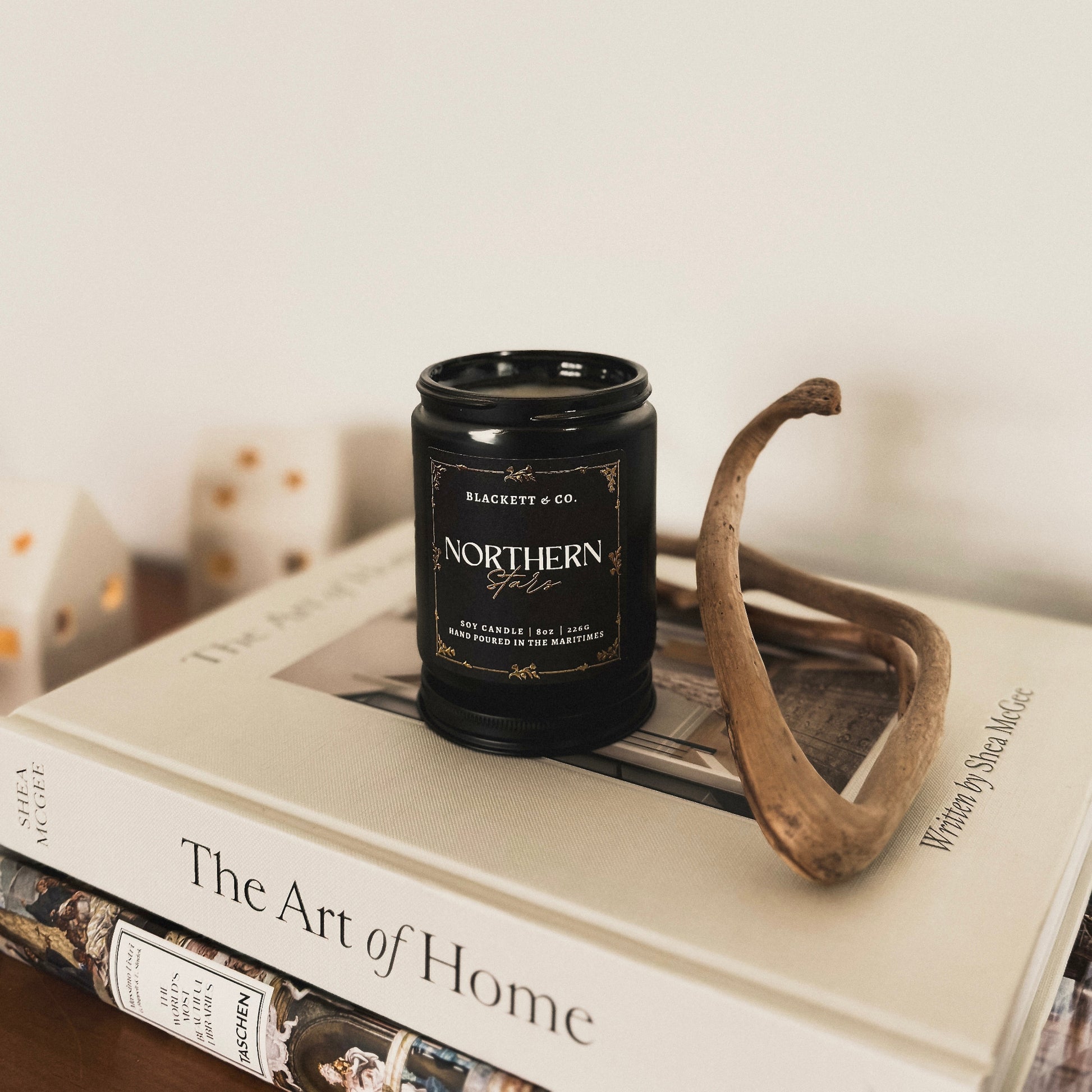 Northern Stars scented natural soy candle on a stack of decorating books
