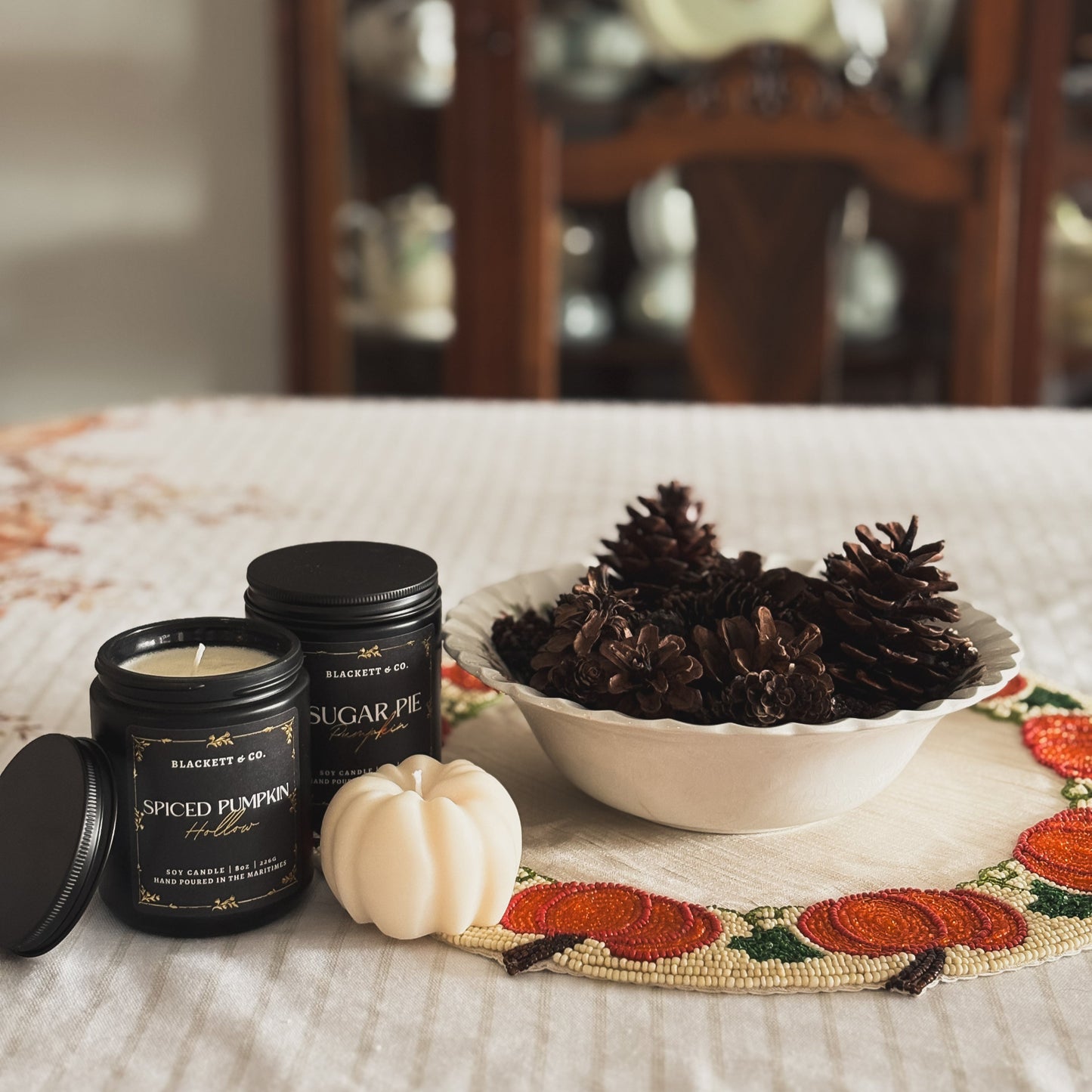 Spiced Pumpkin Hollow and Sugar Pie Pumpkin and a pumpkin-shaped soy candles with a bowl of pine cones.