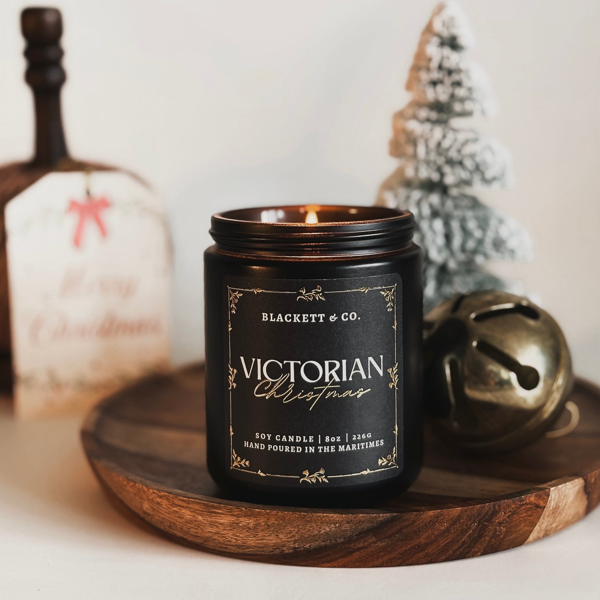 Victorian Christmas scented natural soy candle by Blackett & Co. on a plaid surface with festive decorations.