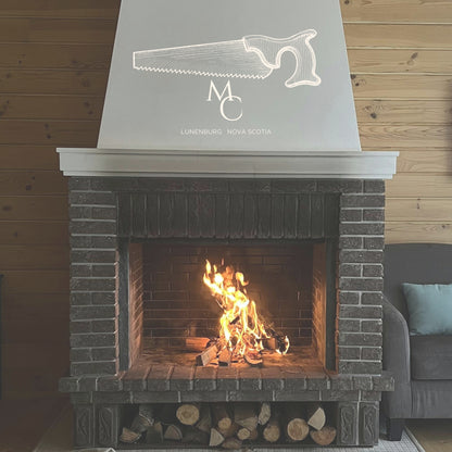 A brick fireplace with a white decorative mantel and a large white logo featuring a line drawing of a saw and text.