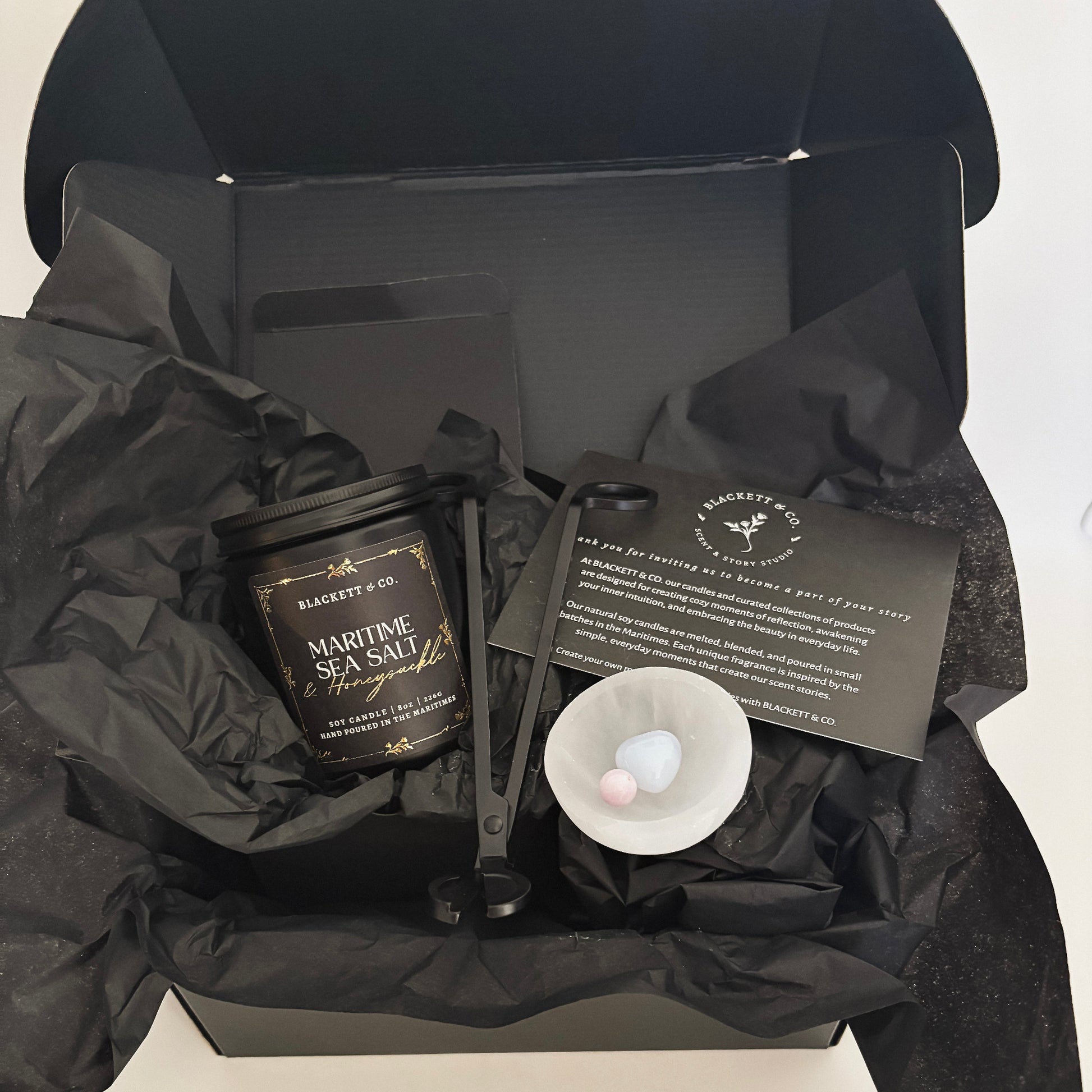 Blackett & Co.'s signature set features a Maritime Sea Salt & Honeysuckle scented natural soy candle, a matte black wick trimmer, a chalcedony heart stone, and kunzite sphere