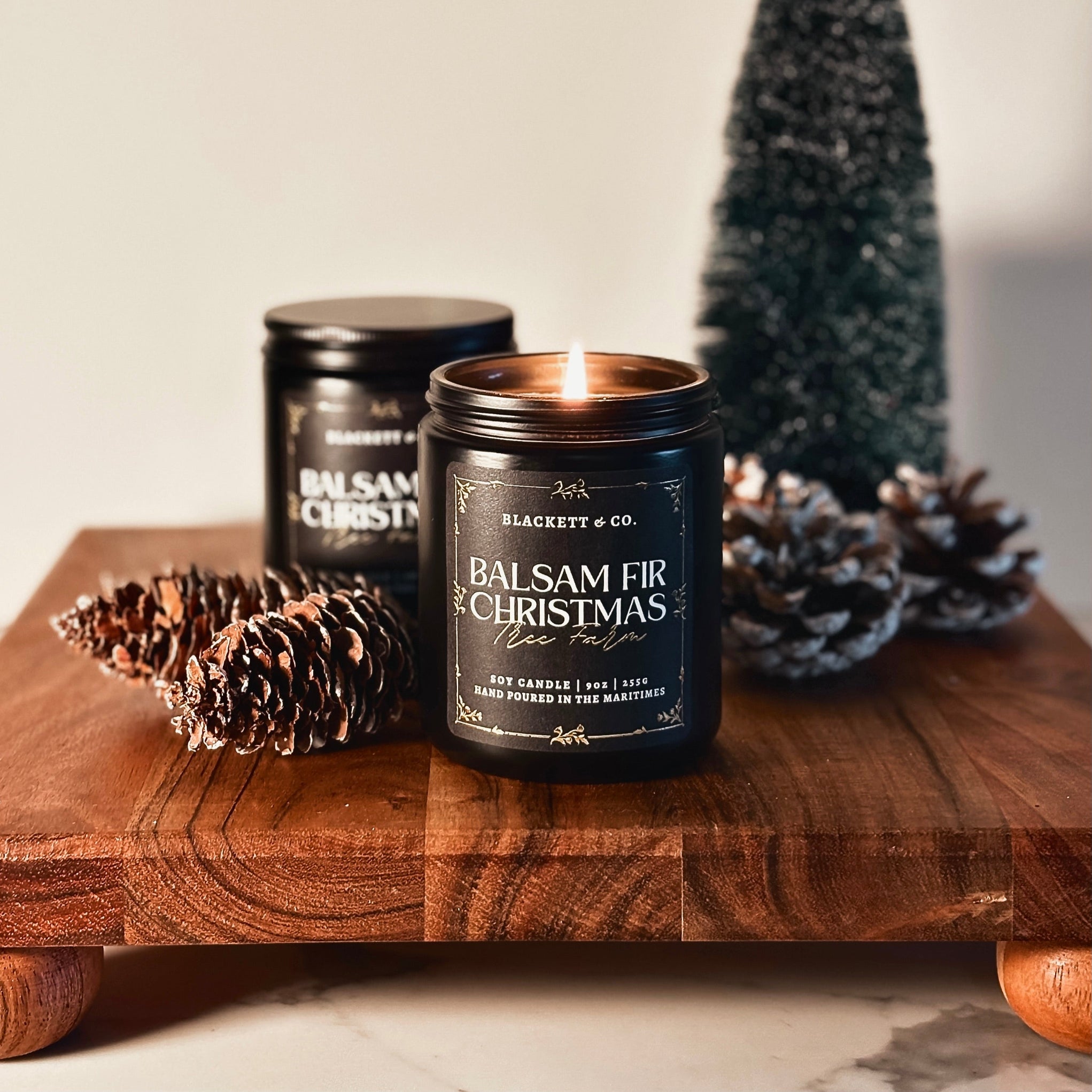 Balsam Fir Christmas Tree Farm scented natural soy candle with pinecones and a small tree on a wooden board.