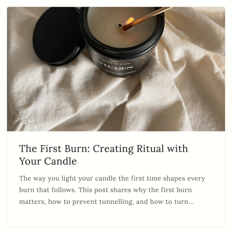Preview of a post from the B&CO. Insider with an image of a Blackett & Co. Kitchen Witch scented natural soy candle with a lit wick on a light fabric background