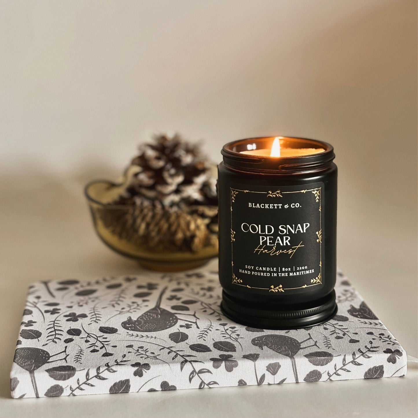Cold Snap Pear Harvest scented natural soy candle hand poured by Blackett & Co. and black bird notebook.