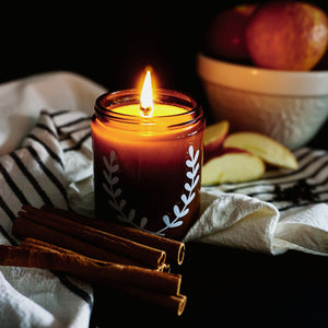 October Eve soy candle, surrounded by cinnamon sticks, whole cloves, and sliced apples, Blackett & Co. soy candles handmade in Halifax, Nova Scotia