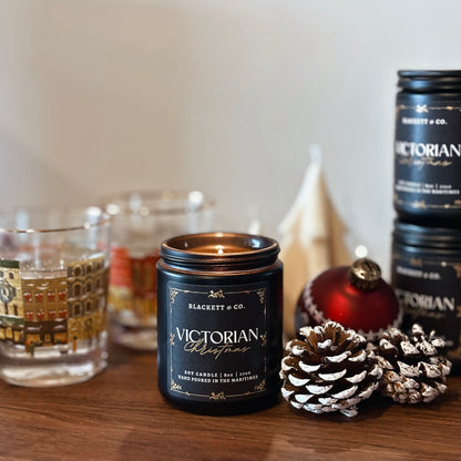 Blackett & Co. Victorian Christmas candle on a wooden surface with a tree-shaped soy candle in the background