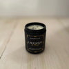 Lavender & Mint scented natural soy candle in a black candle jar by Blackett & Co. on a light wooden surface