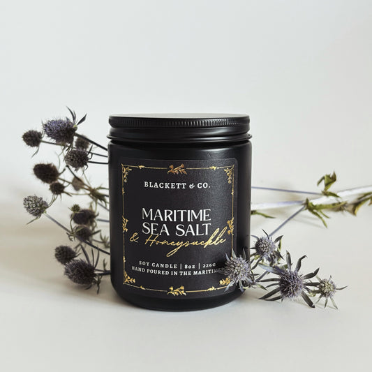 Maritime Sea Salt & Honeysuckle scented natural soy candle surrounded with Nova Scotia thistle
