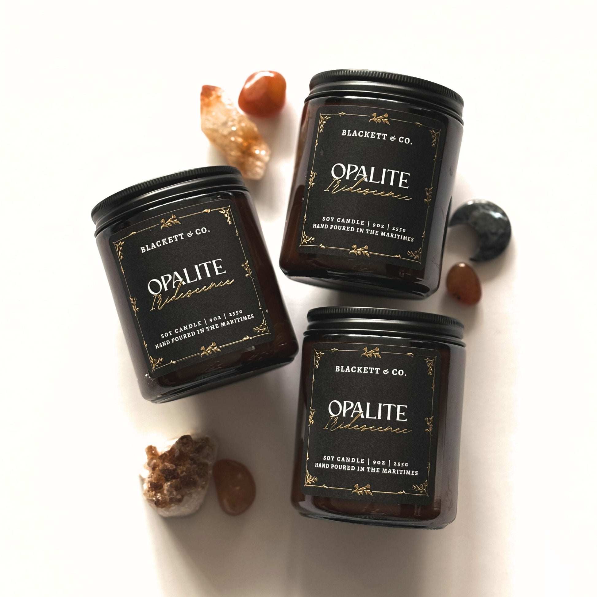 Three Opalite Iridescence scented natural soy candles handmade by Blackett & Co. with decorative stones and crystals on a white background.