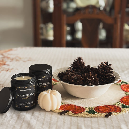 Spiced Pumpkin Hollow and Sugar Pie Pumpkin and a pumpkin-shaped soy candles with a bowl of pine cones.