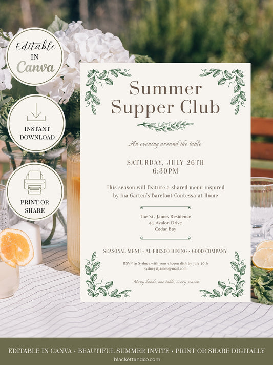 Editable invitation card, featuring a cream background with green leafy borders and elegant typography. The card is displayed on a rustic white-washed wooden table alongside white flowers, a glass of water, and citrus slices.