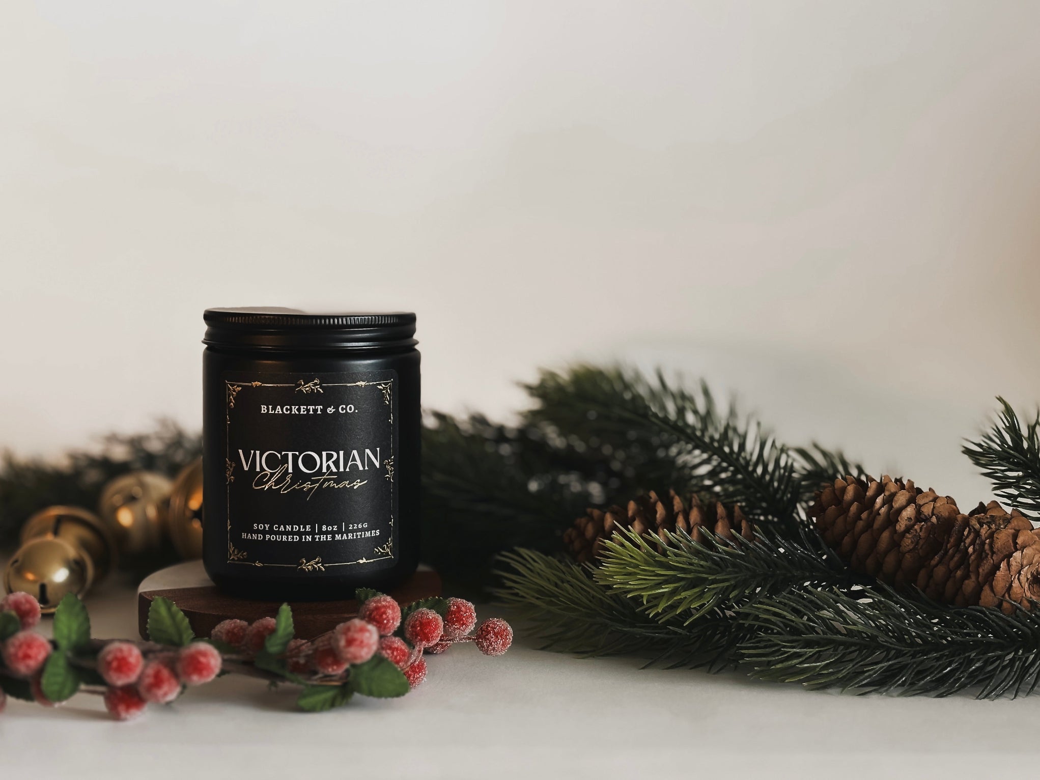 Victorian Christmas scented natural soy candle hand poured by Blackett & Co. with decorative berries and pine on a light background.
