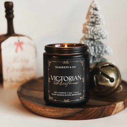 Victorian Christmas scented natural soy candle by Blackett & Co. on a plaid surface with festive decorations.